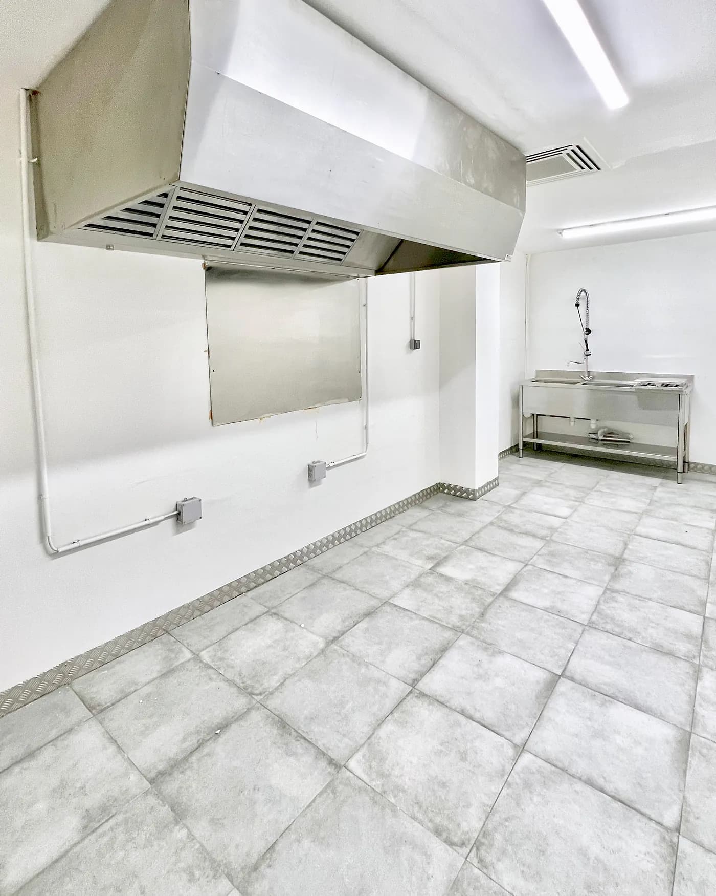 Laboratoire Hub Kitchen : hotte inox à filtres, crédence inox et plonge inox avec douchette